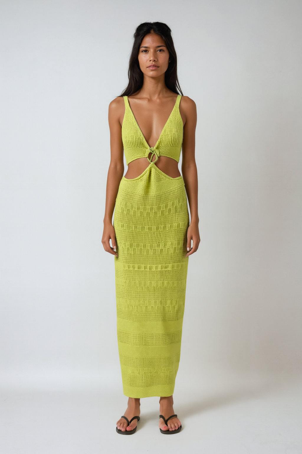 Woman wearing a bright green dress with cut-out design on a white background